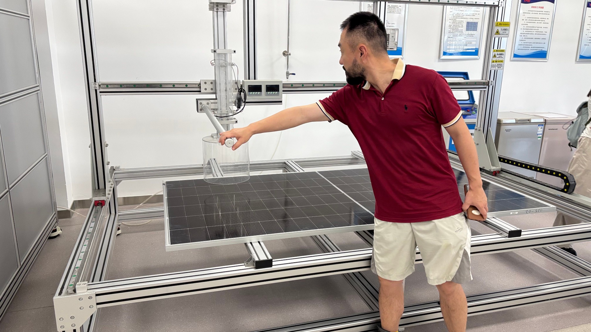 Researcher operating experimental testing apparatus over a solar panel in a materials laboratory