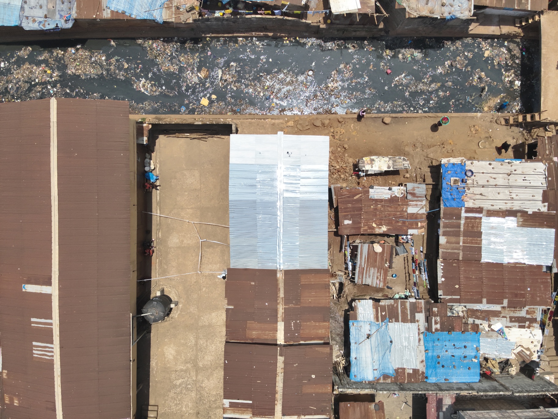 Aerial view of a completed reflective rooftop installation among tin-roofed homes in Freetown