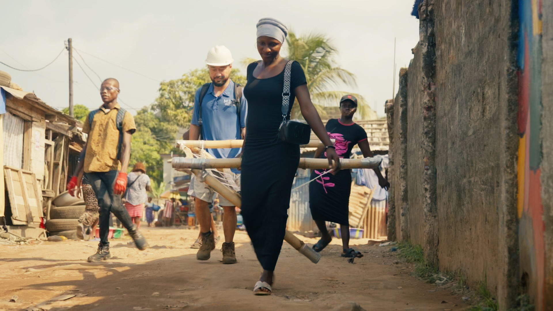 Carrying a bamboo canopy frame through the neighbourhood