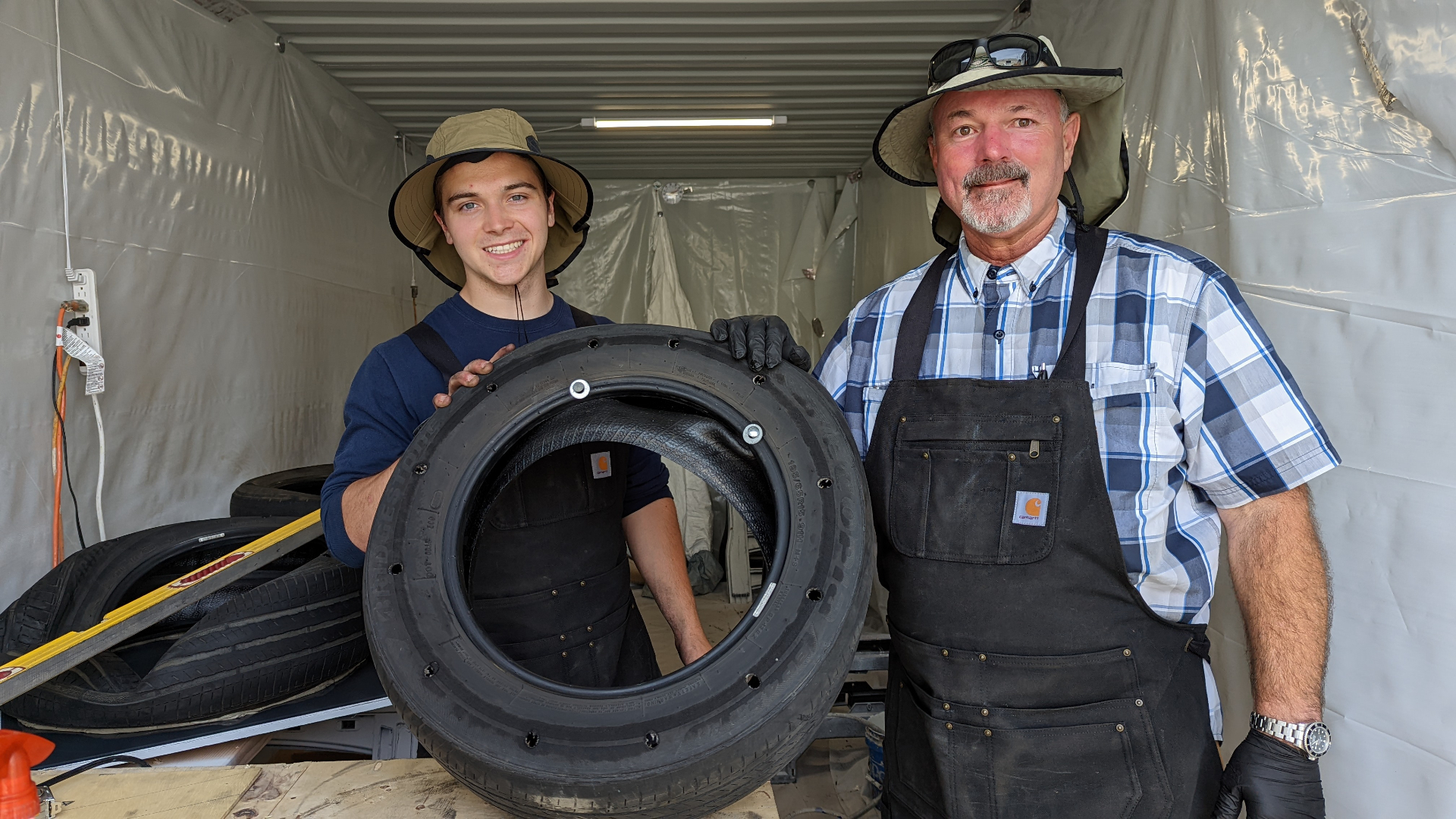 Two members of the research team with an instrumented tire assembly — part of the fabrication work behind the reflective rooftop testbed.